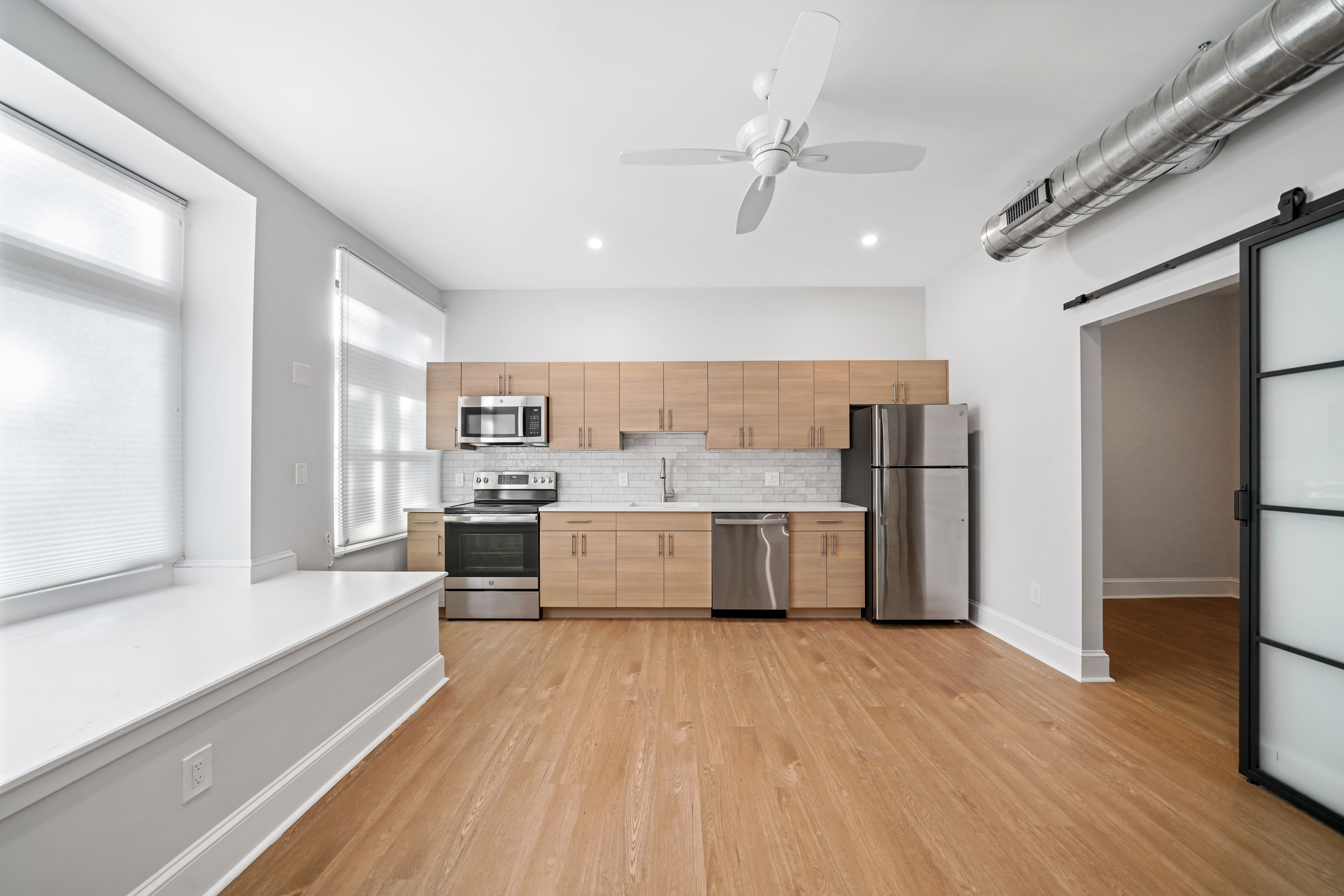 a living room with a kitchen and a ceiling fan